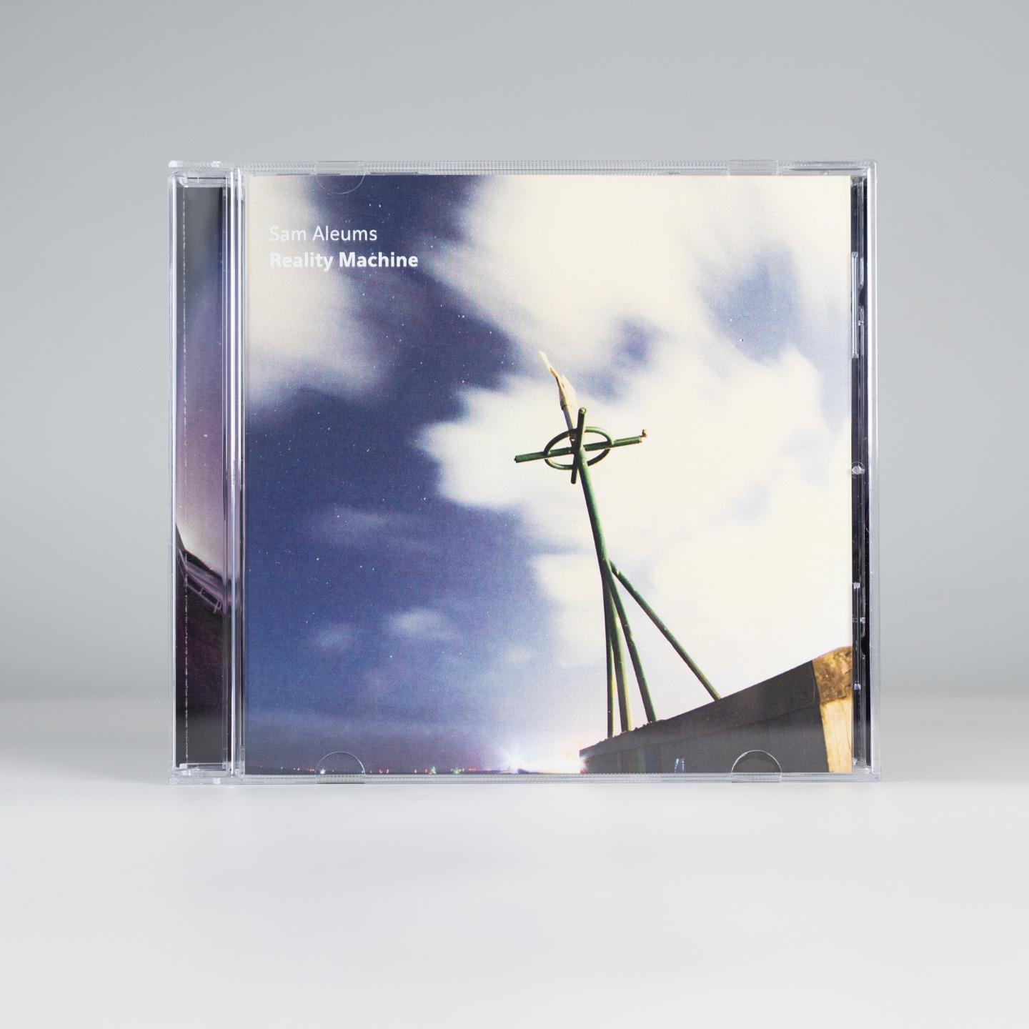 A compact disk from the front. a weathervane stands against a dusky sky, and the text "Sam Aleums Reality Machine" on the top right corner