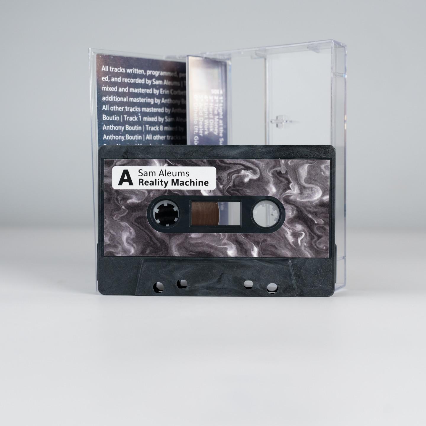 the cassette case open to reveal the tape, black marble swirl with a smoky marble label bearing the title of the work